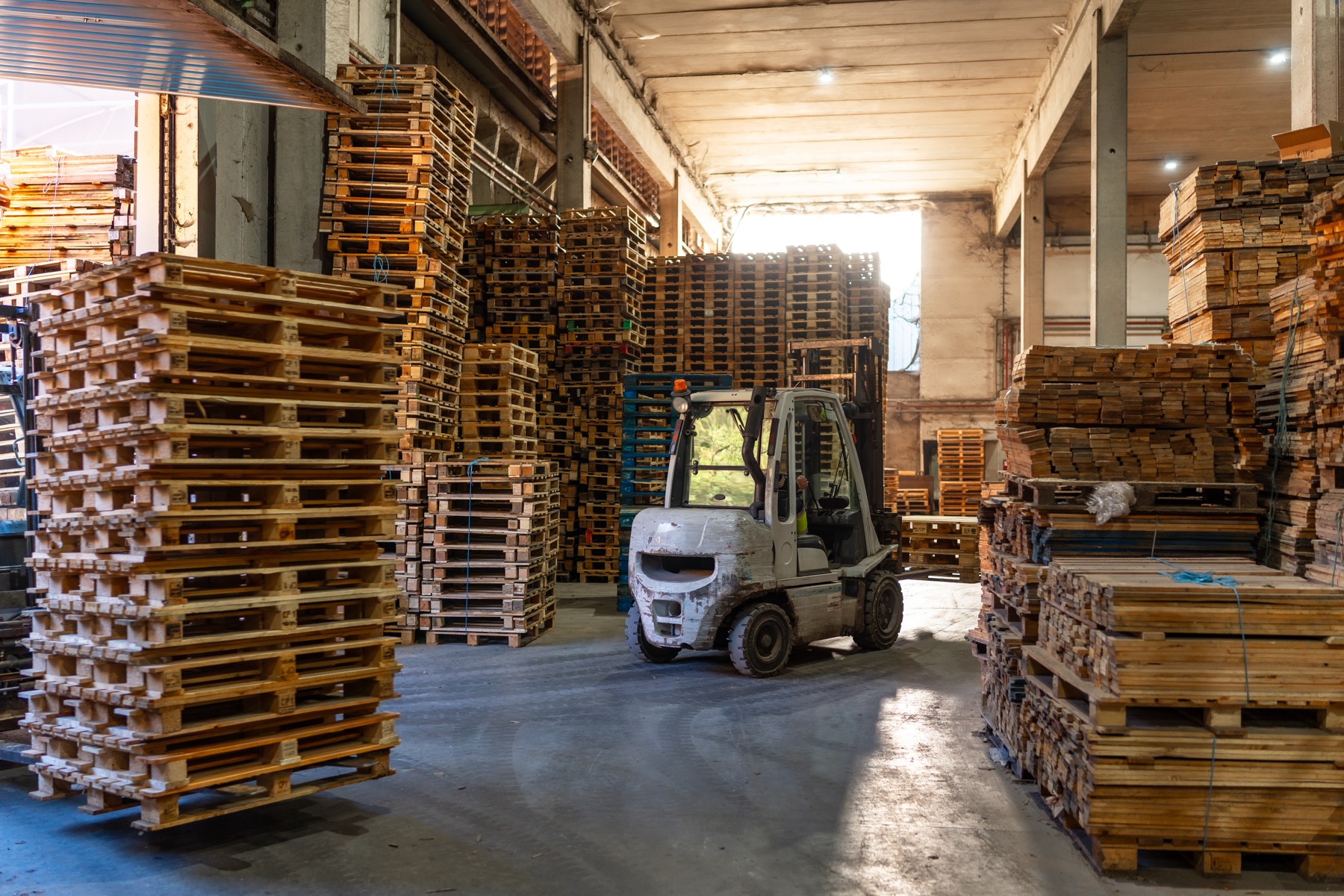 Wooden pallets stacked beside a forklift in a warehouse