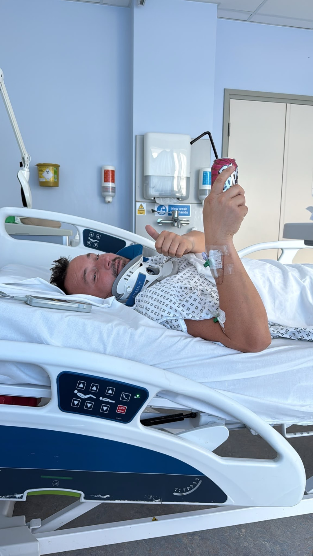 Alex Tyrrell giving a thumbs-up from his hospital bed after a serious motorcycle accident