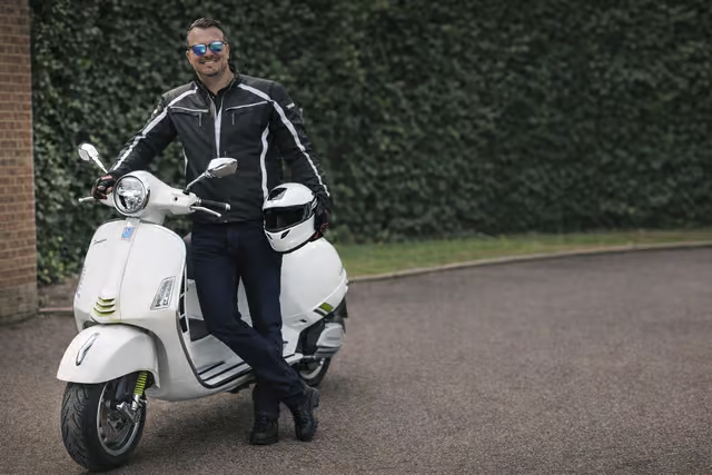 Alex Tyrrell standing beside the white Vespa used for the Pompey to Pompeii ride