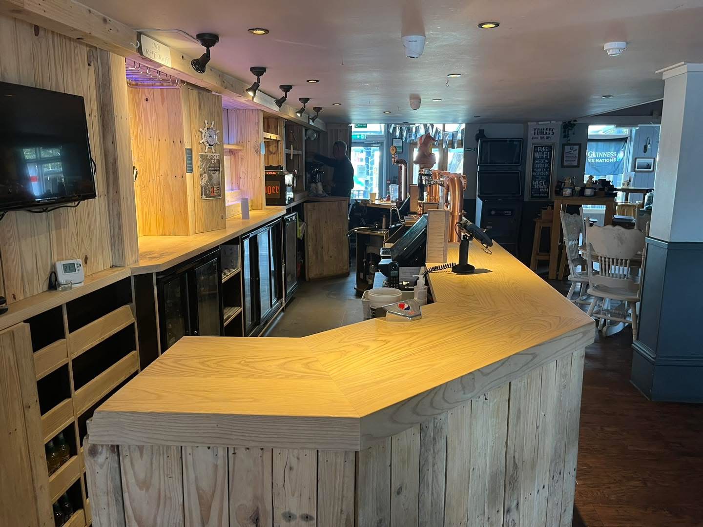 Curved pub bar front clad with reclaimed pallet boards during refurbishment