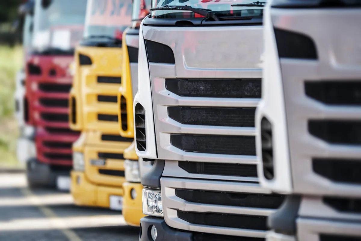 Curtain-side and flatbed collection lorries lined up in a depot yard
